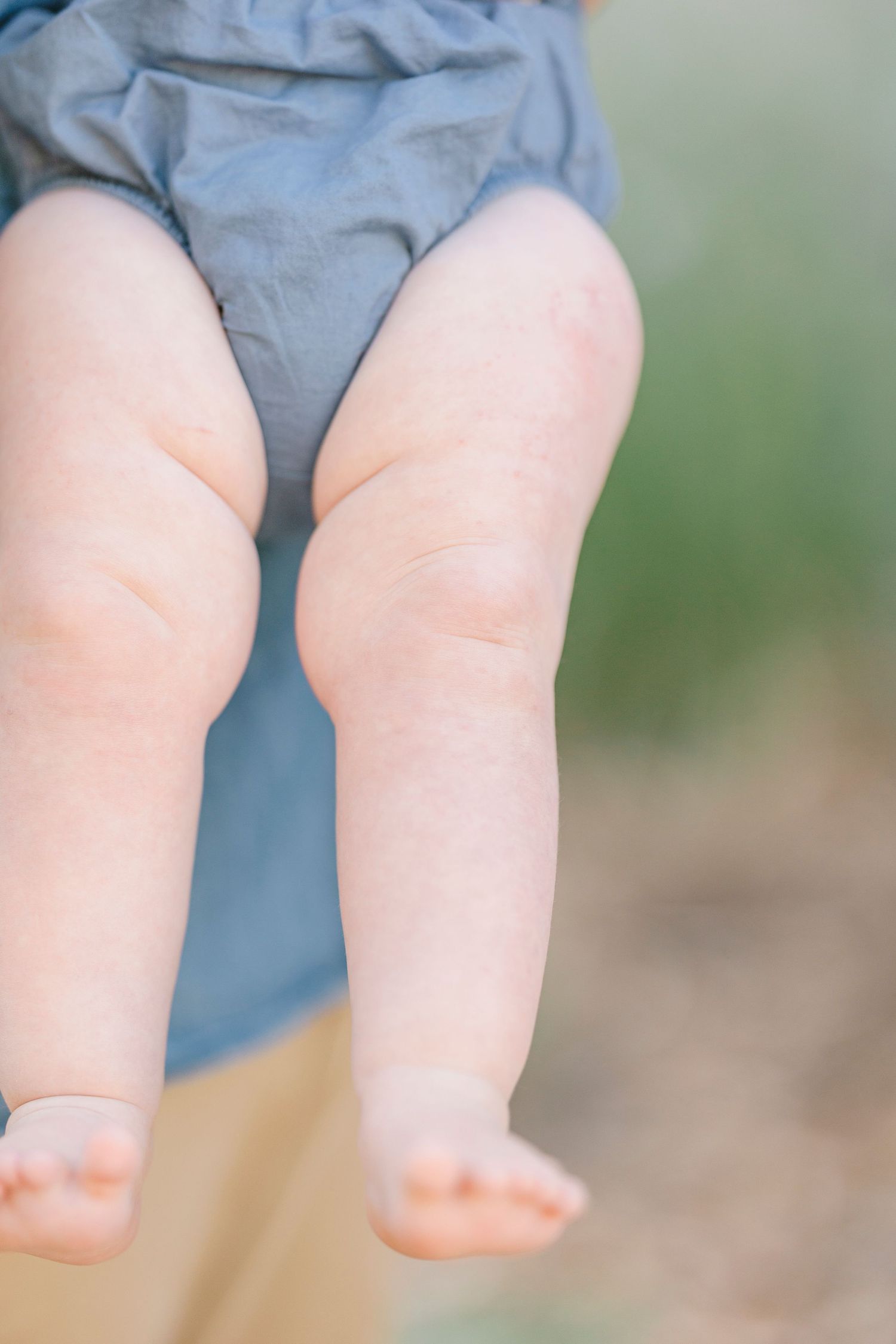 Close-up detail shot of baby's chubby legs in soft lighting.