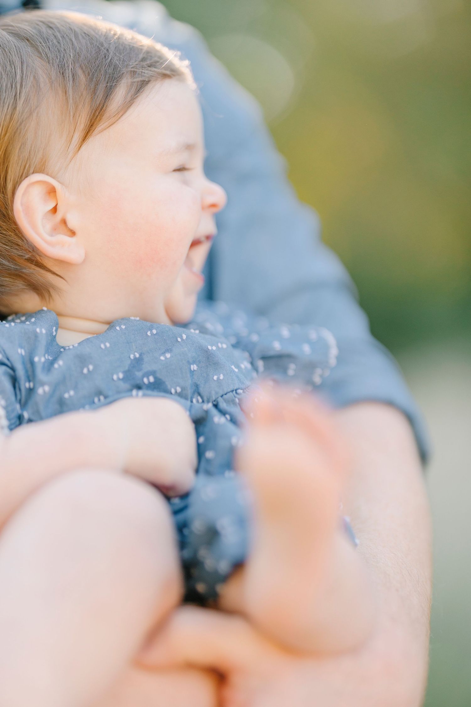 Side profile of a baby wearing a dotted blue outfit during an outdoor photoshoot.