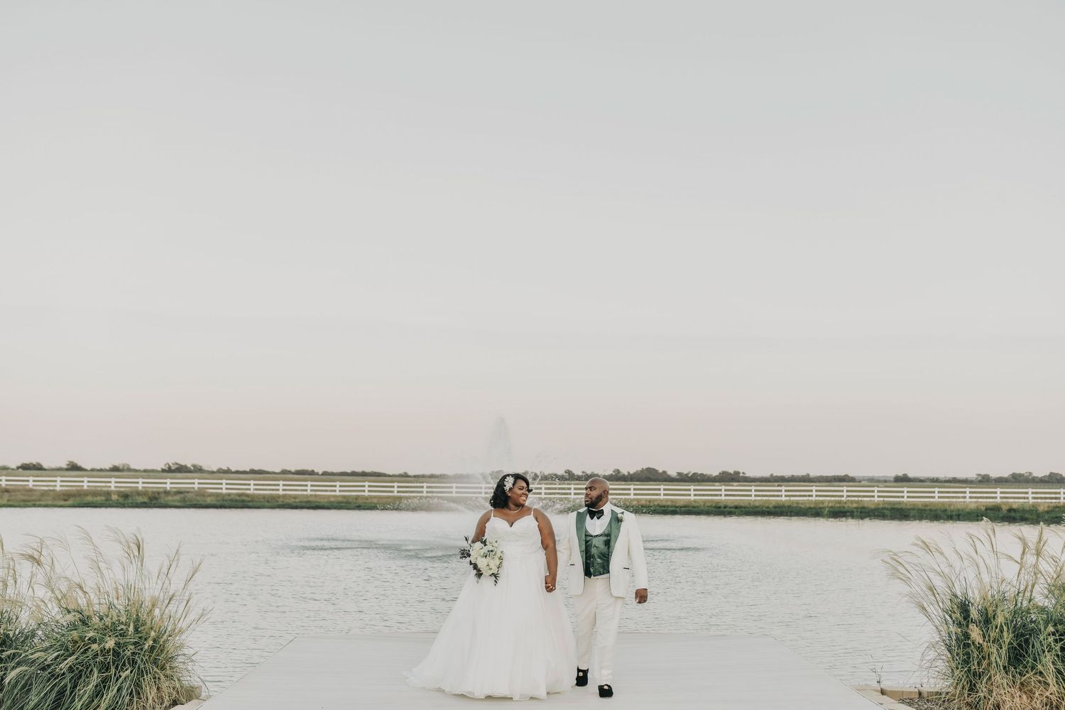 a bride and groom walk away from the pond at sunset at the gardenia