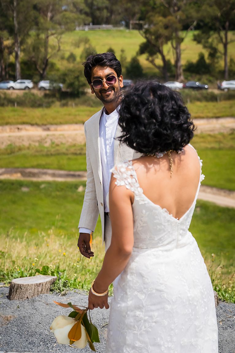 Joyful couple in wedding attire walking together outdoors with bride in white dress and groom in light suit.