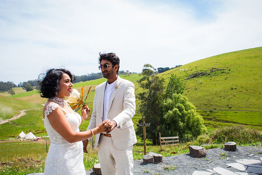 Wedding couple shares an intimate moment on an outdoor terrace with scenic rolling hills behind them.
