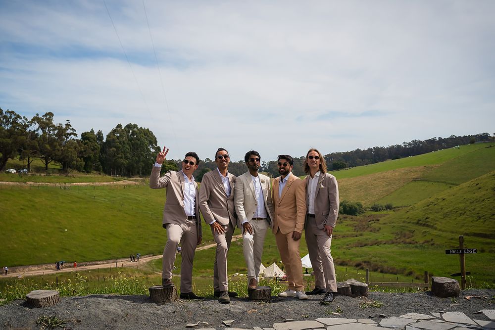Group of people standing together on a hillside overlooking green rolling pastures on a sunny day.