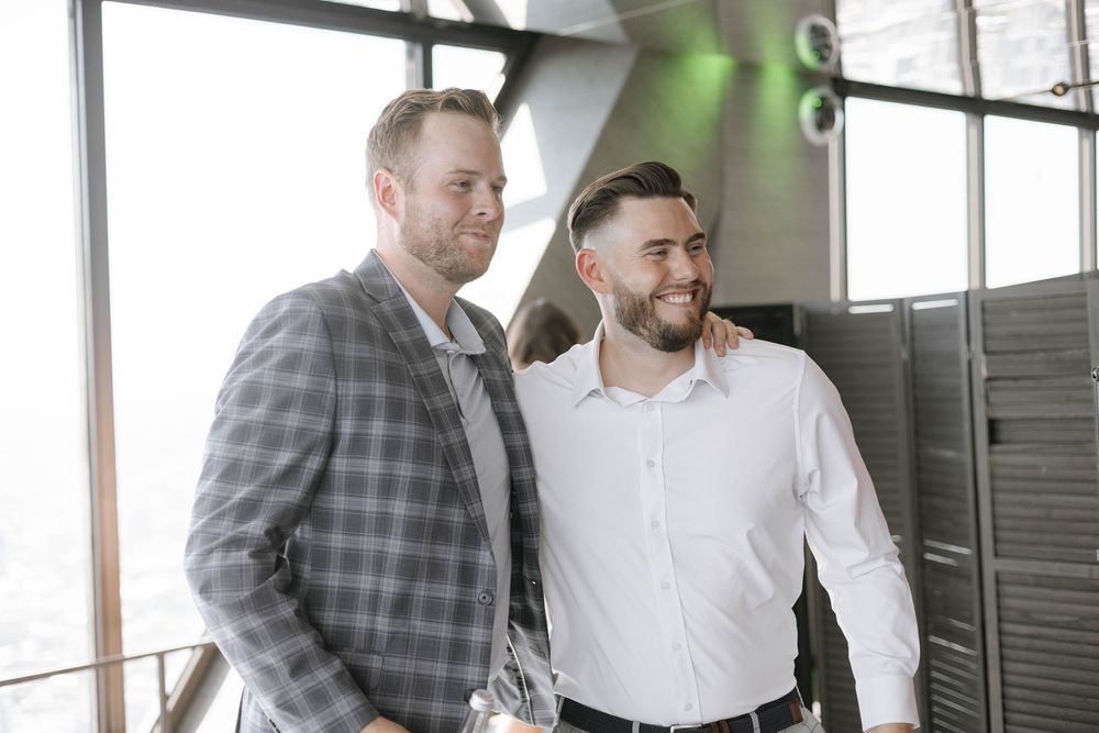 Three men in office attire collaborate while looking at digital device screens during a business meeting.