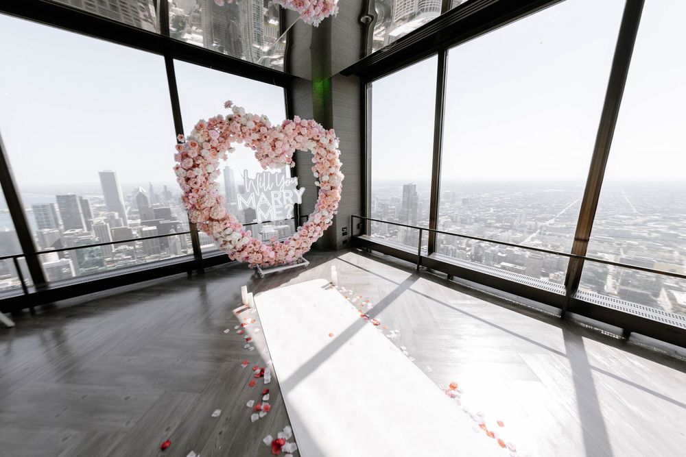 Panoramic window views of a cityscape through large glass panels with tropical flower decorations.