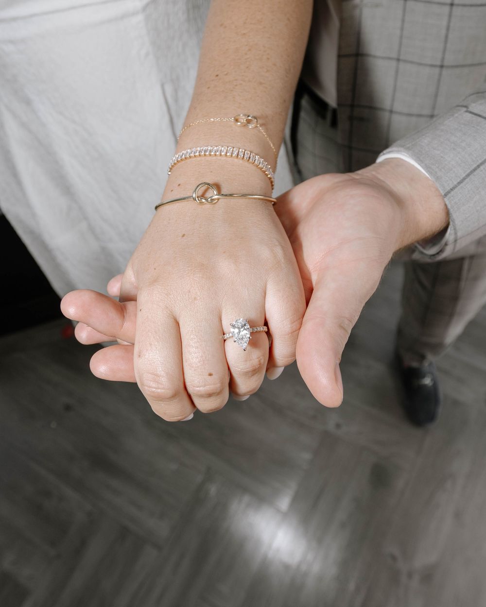 Delicate jewelry styling of layered gold bracelets and rings with diamonds arranged in various positions on hands.