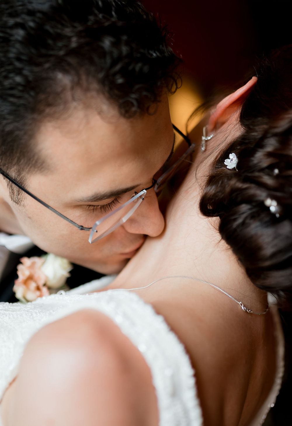 A close-up sequence of a tender kiss between newlyweds wearing glasses against a soft white background.