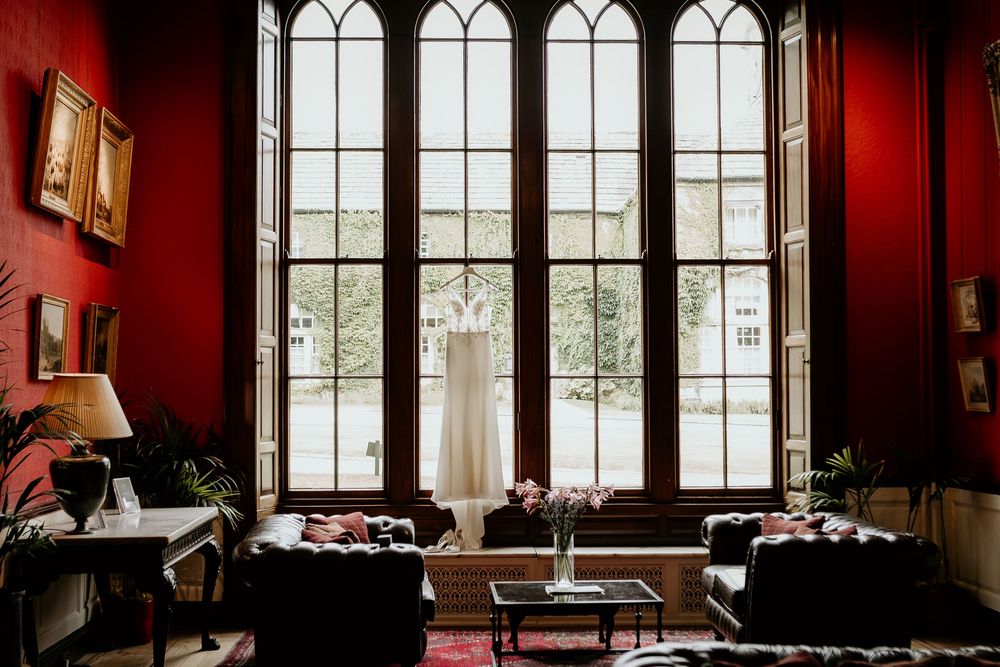 Elegant interior room with Gothic-style arched windows, deep red walls, and period furniture bathed in natural light.