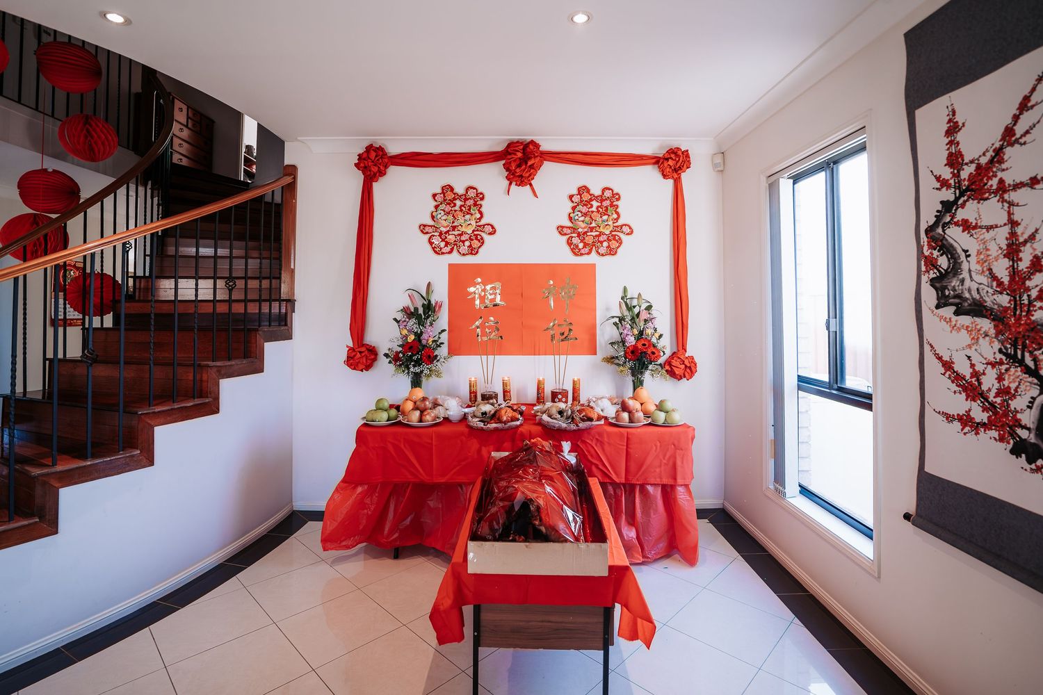 Modern interior with wooden staircase decorated with red Chinese New Year lanterns and paper cutouts.