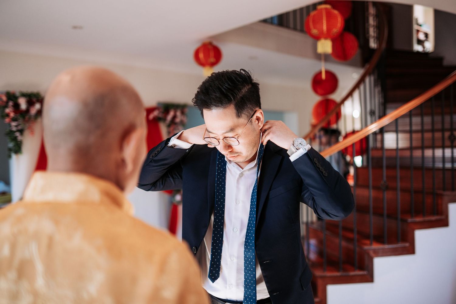 A groom adjusts his tie and gets ready during traditional Chinese wedding preparations.