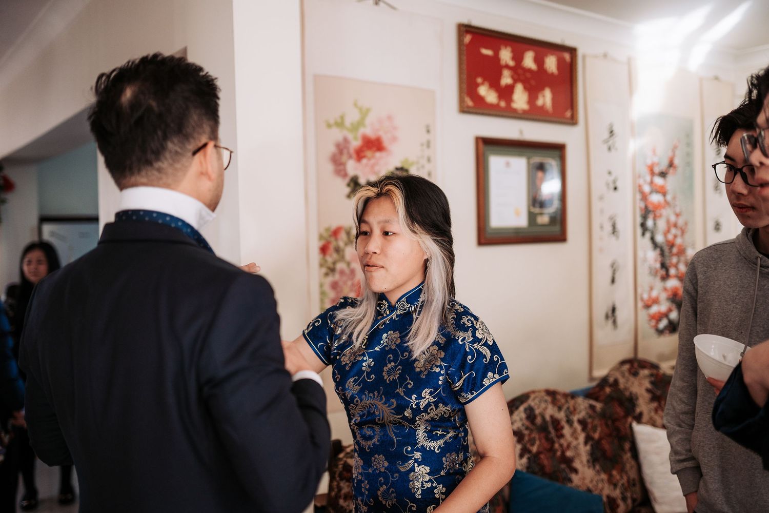 Guests in formal attire conversing with traditional Chinese decor in background.