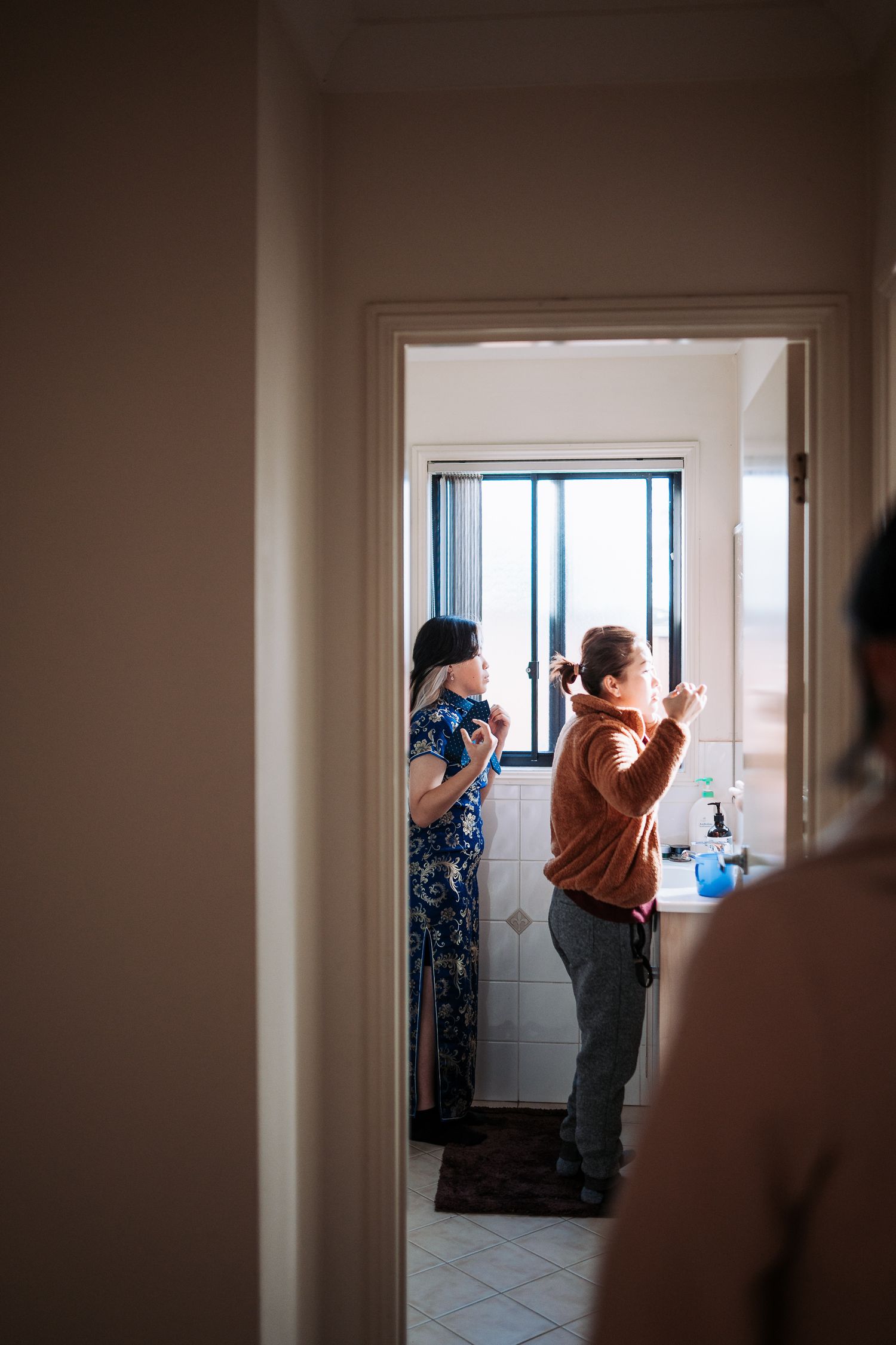 Silhouetted figures gathering near a bright window in a dimly lit hallway.