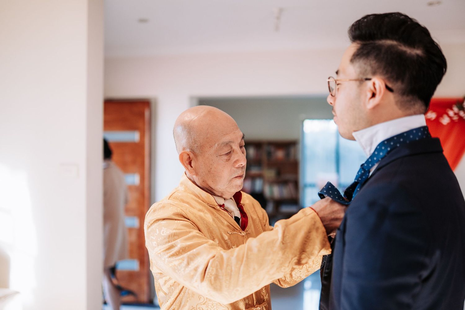 Two people having a conversation in an indoor setting with one wearing an orange jacket.