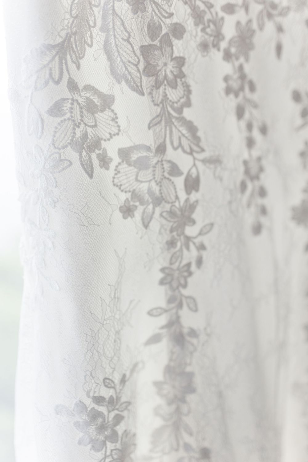 White sheer curtain with delicate floral pattern casting soft shadows in natural light.