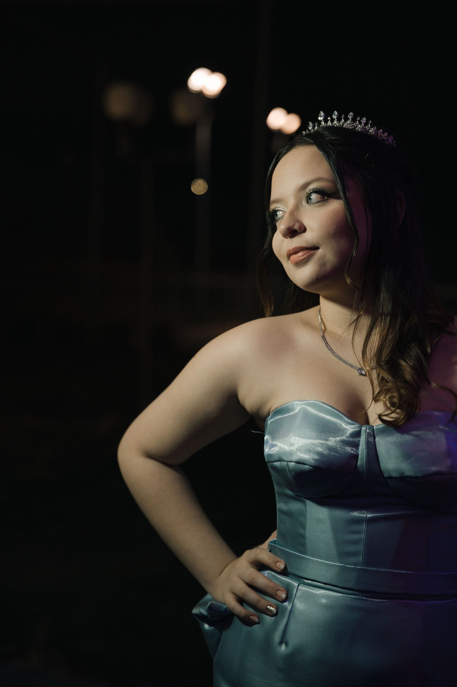 A figure in a teal strapless dress poses against a dark background in a series of dramatic cropped shots.