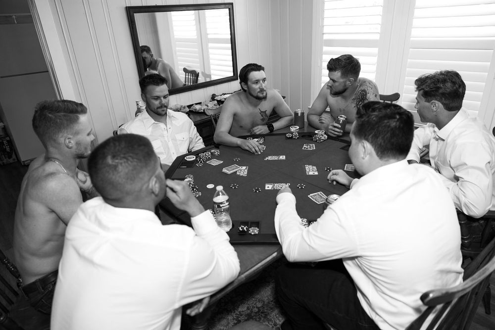 Wedding party gathered around a table playing cards and celebrating together.