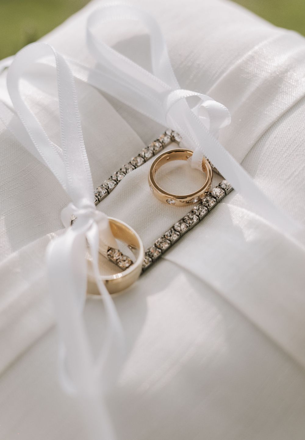 A sequence of silver and gold engagement rings with diamonds rests elegantly on white satin ribbon.