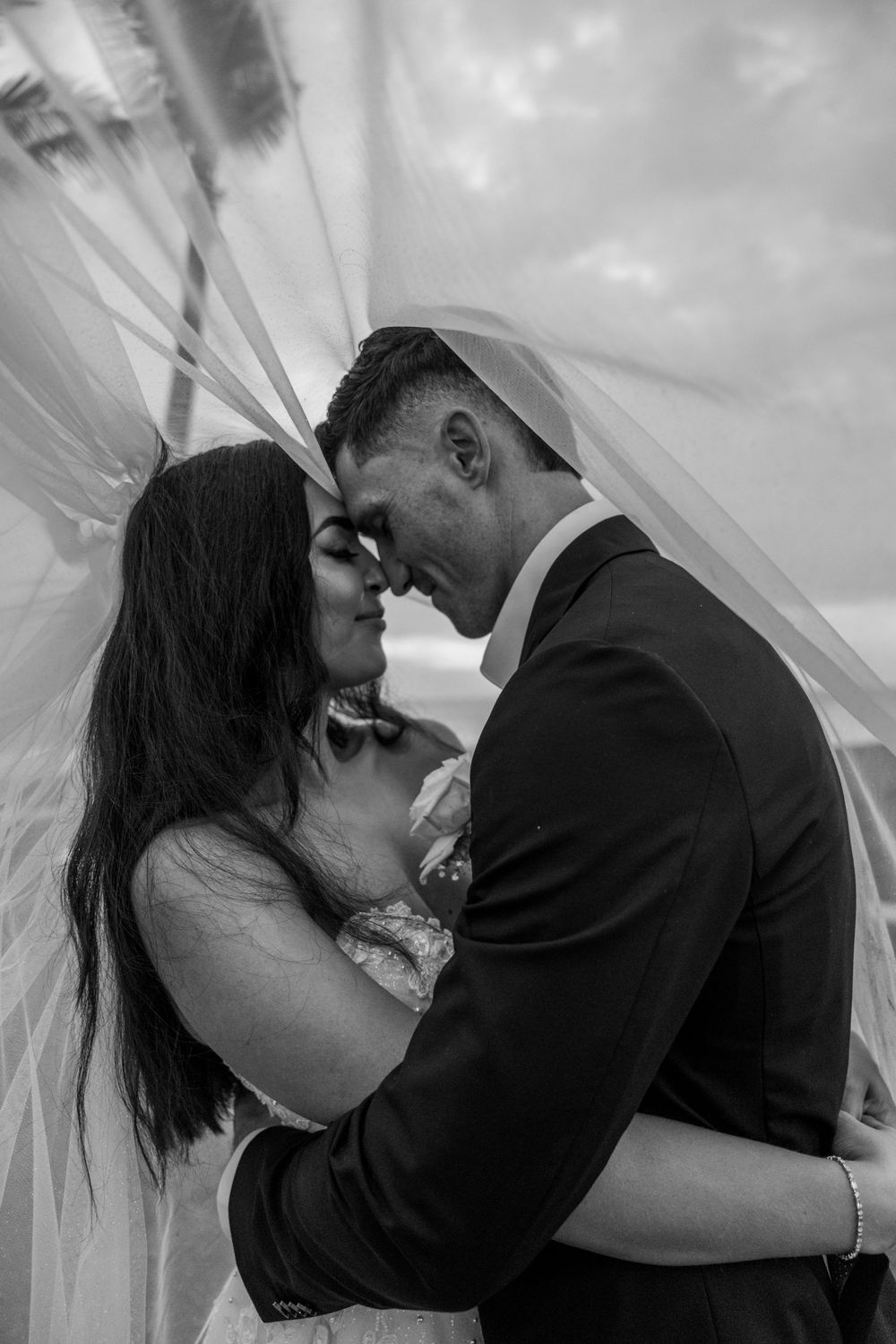 Romantic black and white sequence of moments showing a couple embracing under a flowing veil during their wedding.
