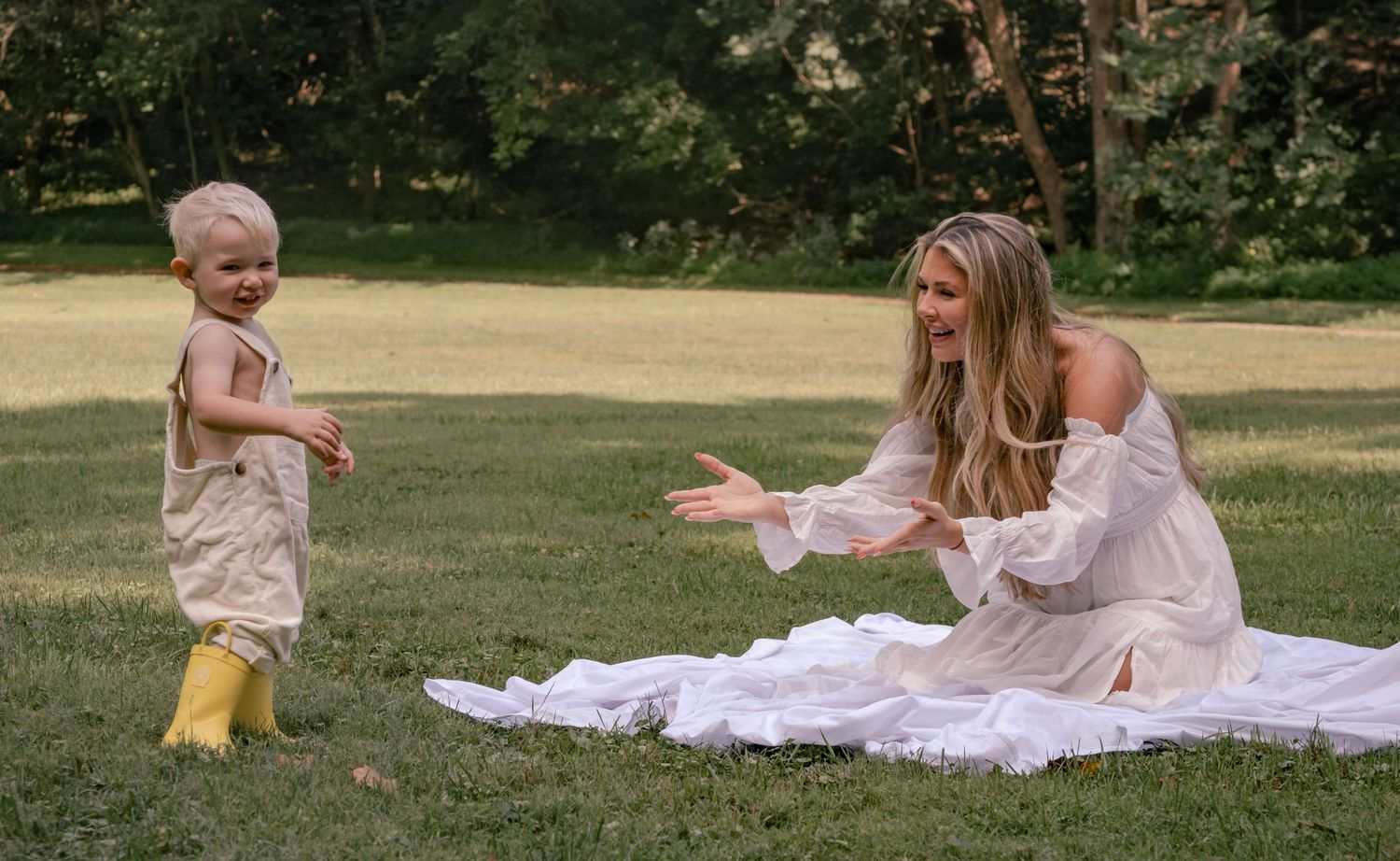 Playful interaction on a sunny lawn with a white blanket spread out on the grass.