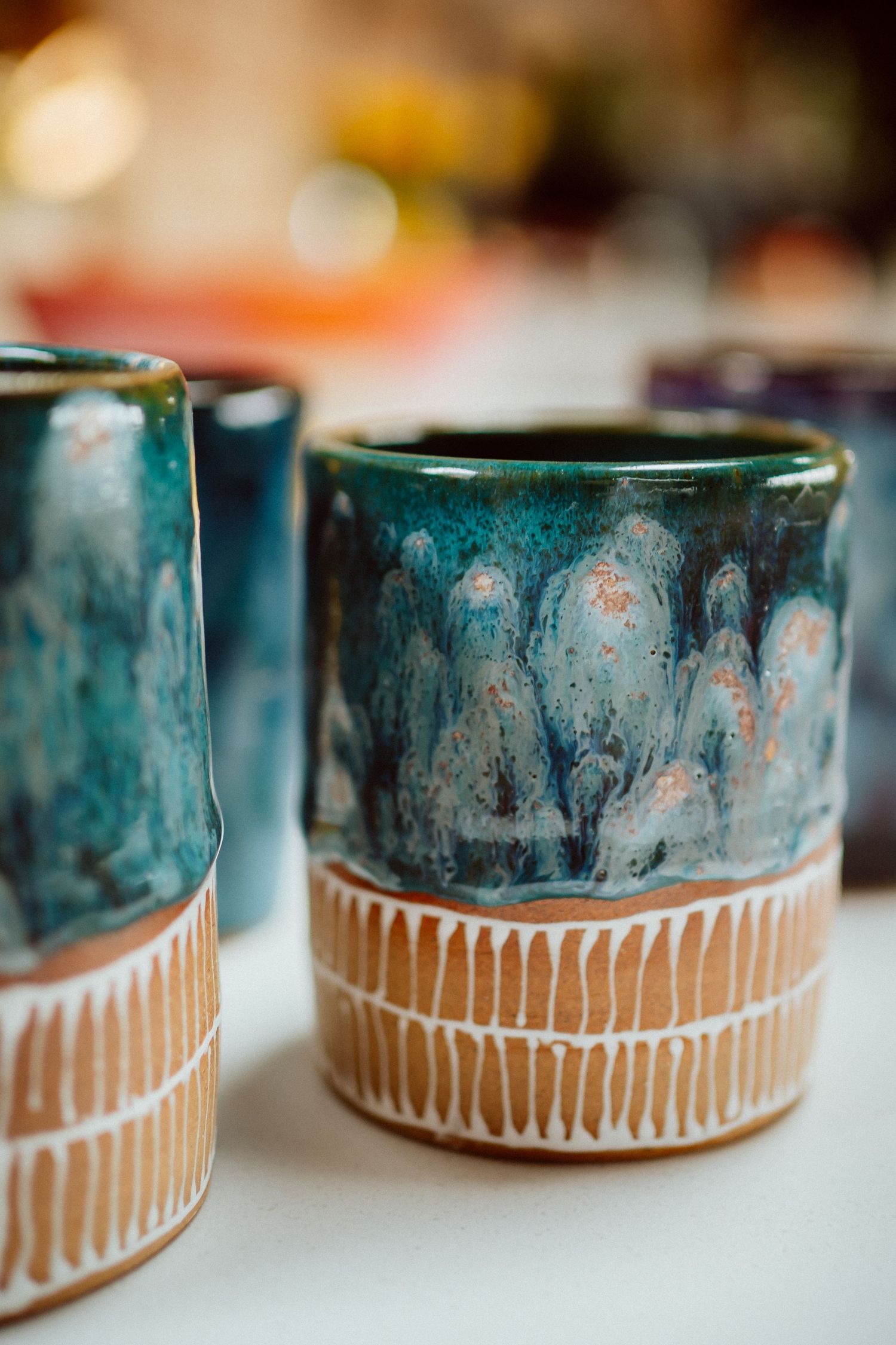 A close-up view of handmade ceramic bowls with a unique teal glaze and tan striped pattern along the base.