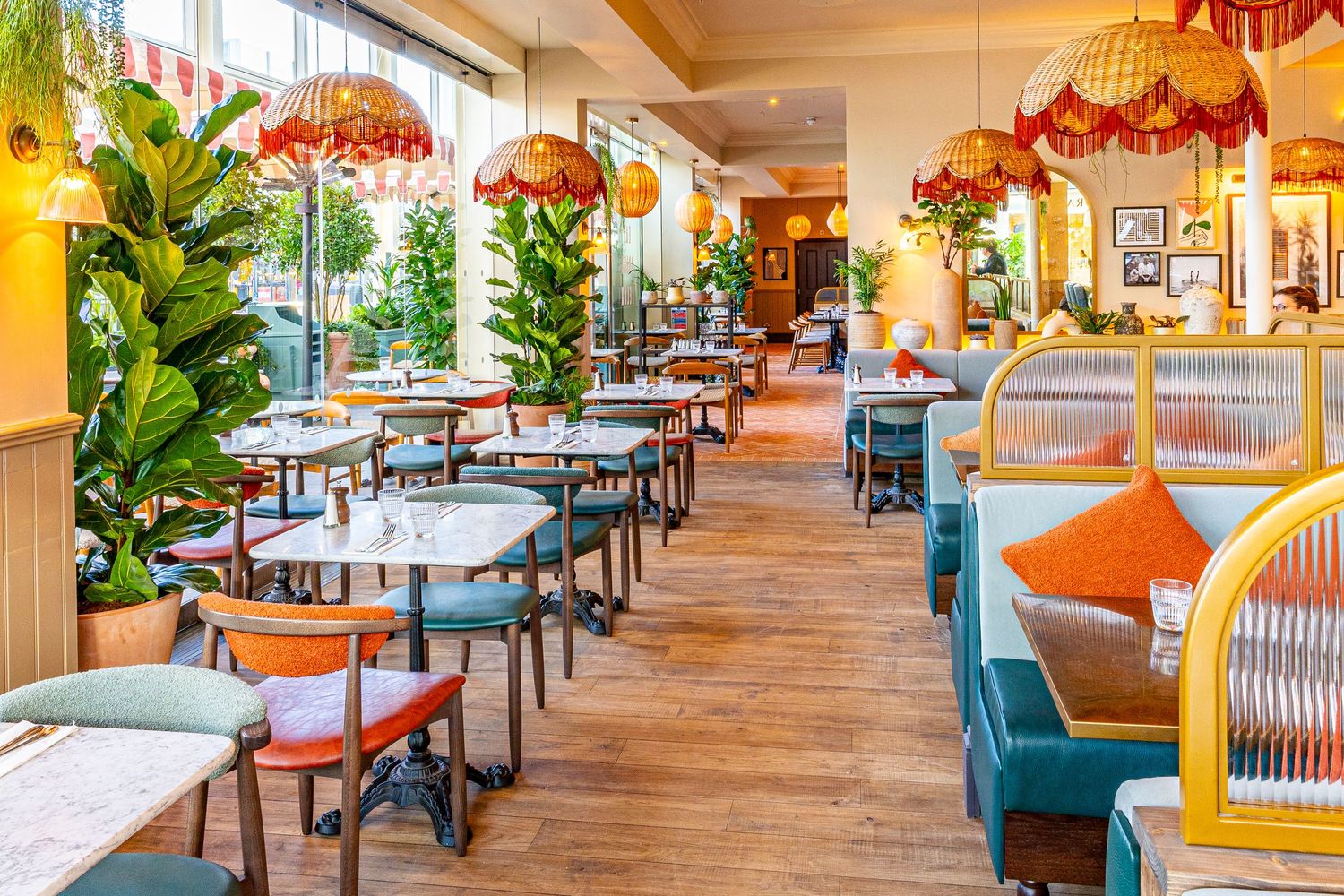 Modern restaurant interior with colorful umbrellas hanging from ceiling and plush seating arrangements in warm lighting.