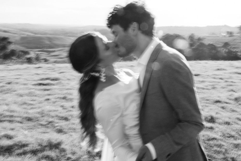 Black and white romantic moment captured in a rural hillside setting.