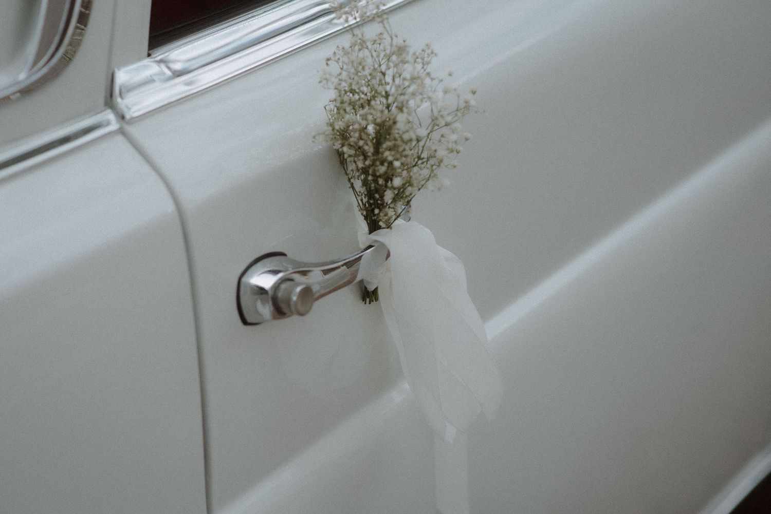 A vintage white Rolls Royce parked in an elegant setting.