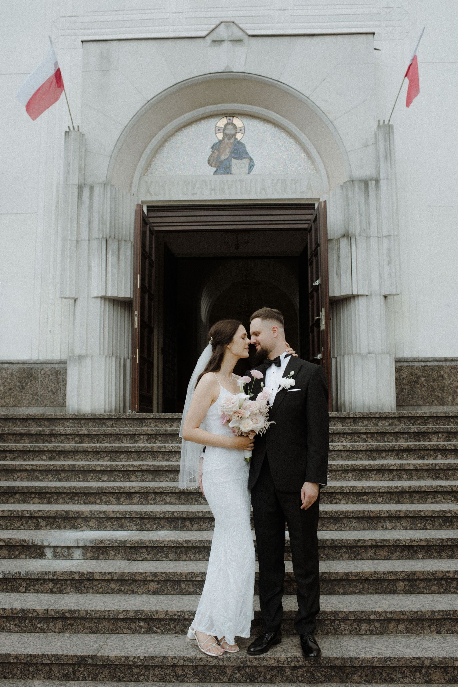 Romantic wedding photos on white church steps with architectural details.