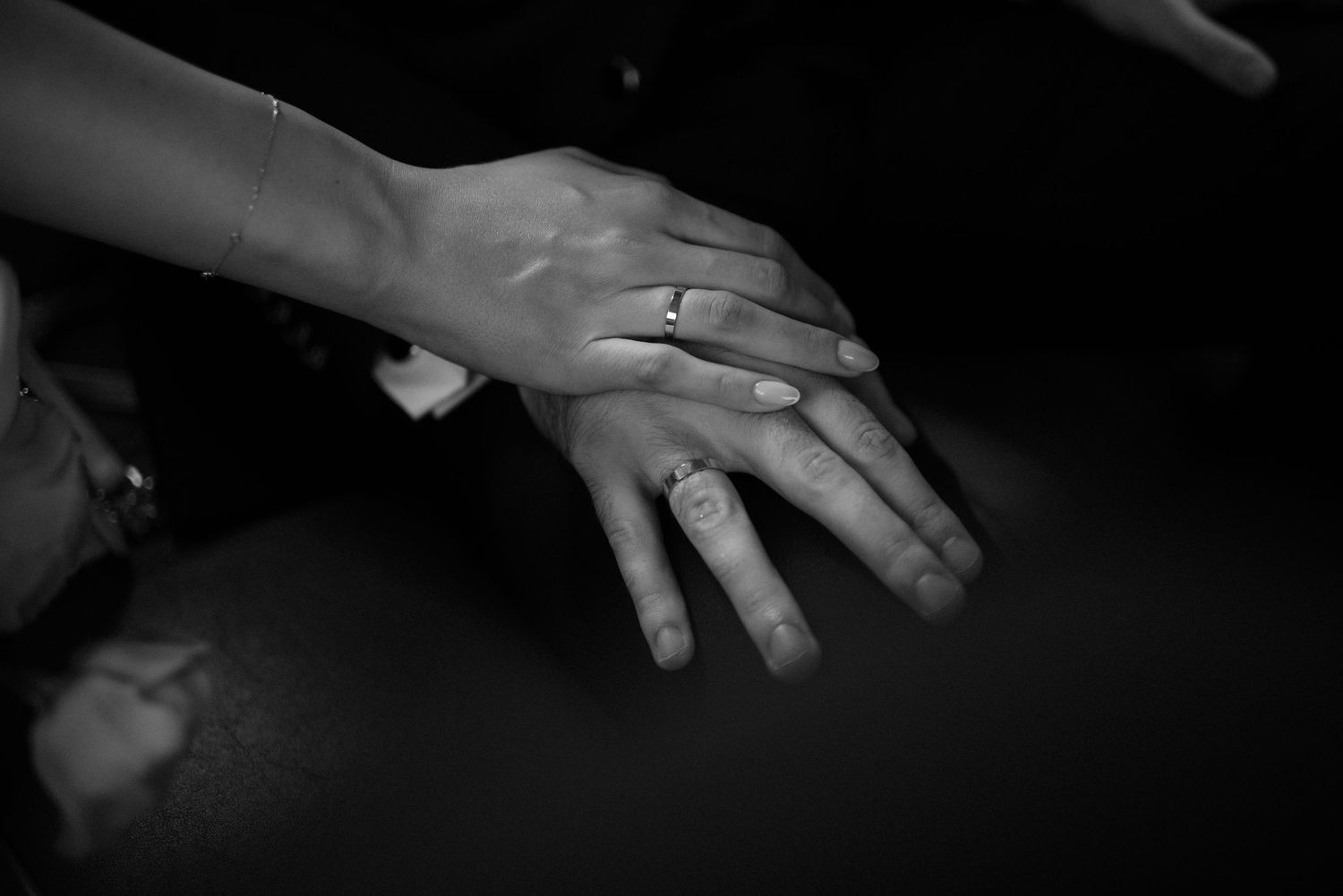 Closeup of hands with wedding rings being exchanged during an intimate ceremony.