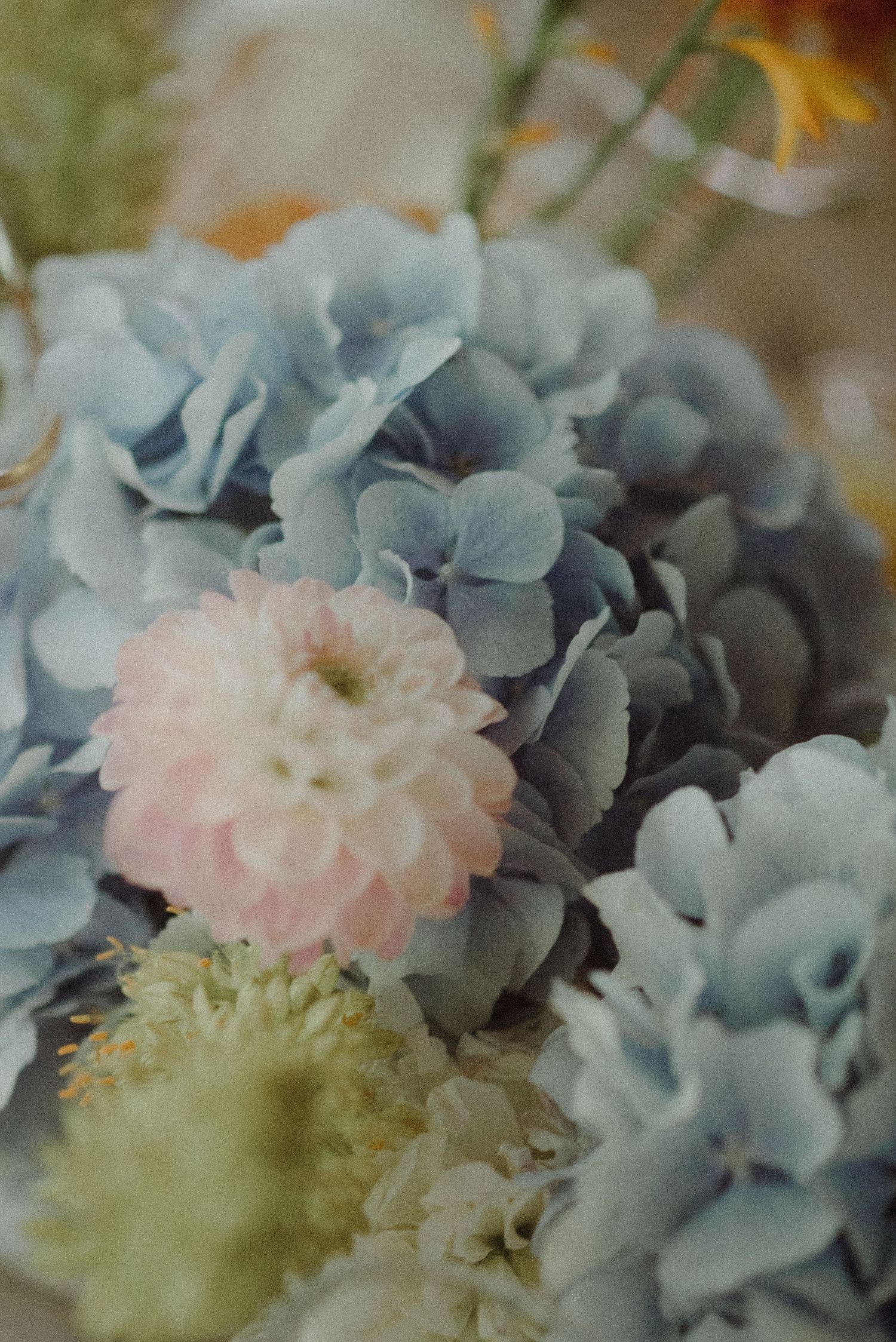 Delicate floral arrangement with soft blue hydrangeas and pink blooms.