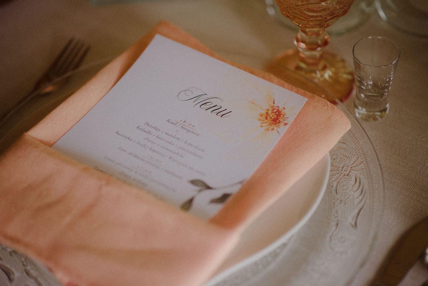 Elegant place settings at wedding reception with menu cards and glassware.