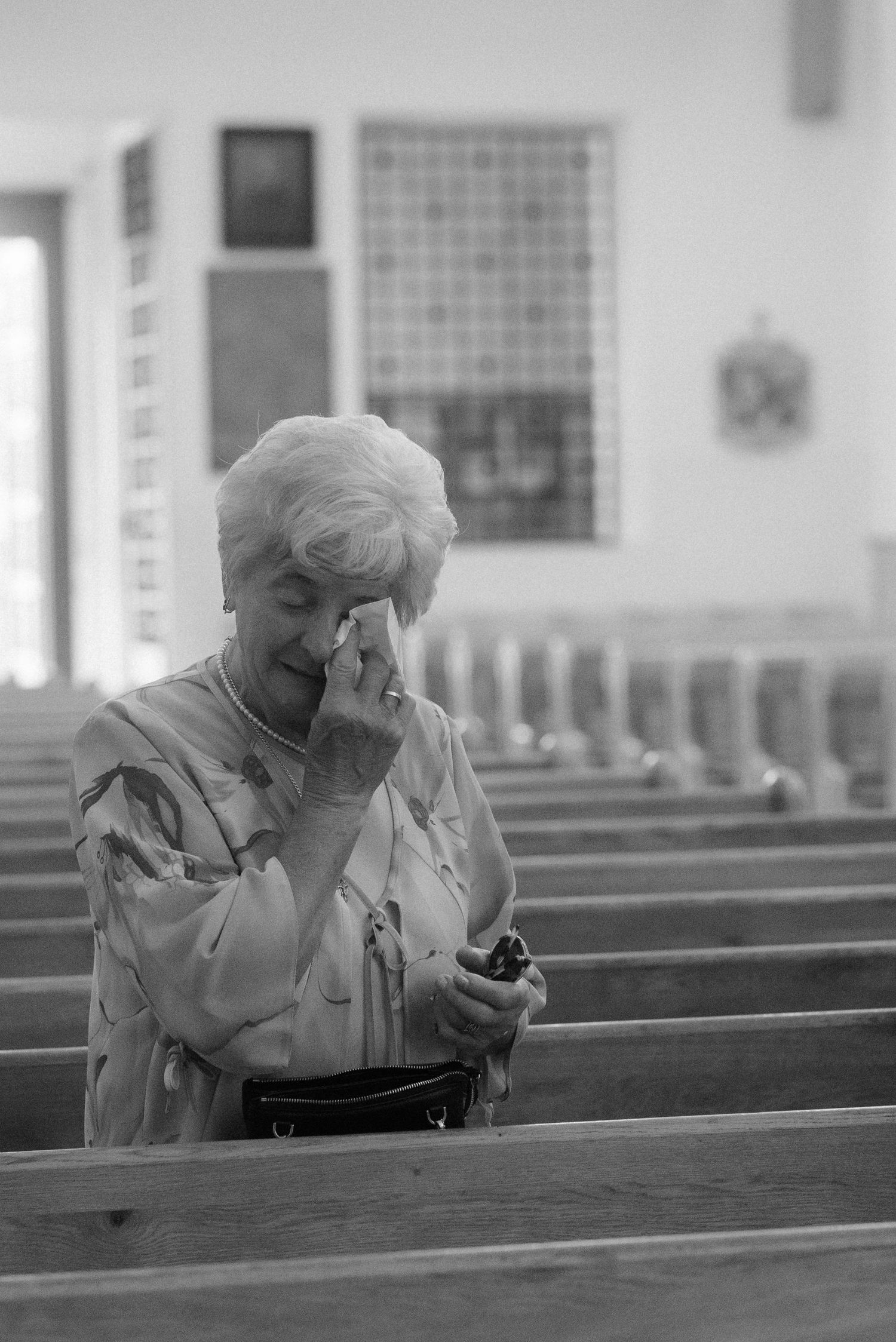 Series of black and white photos showing a person praying while seated in a church pew.