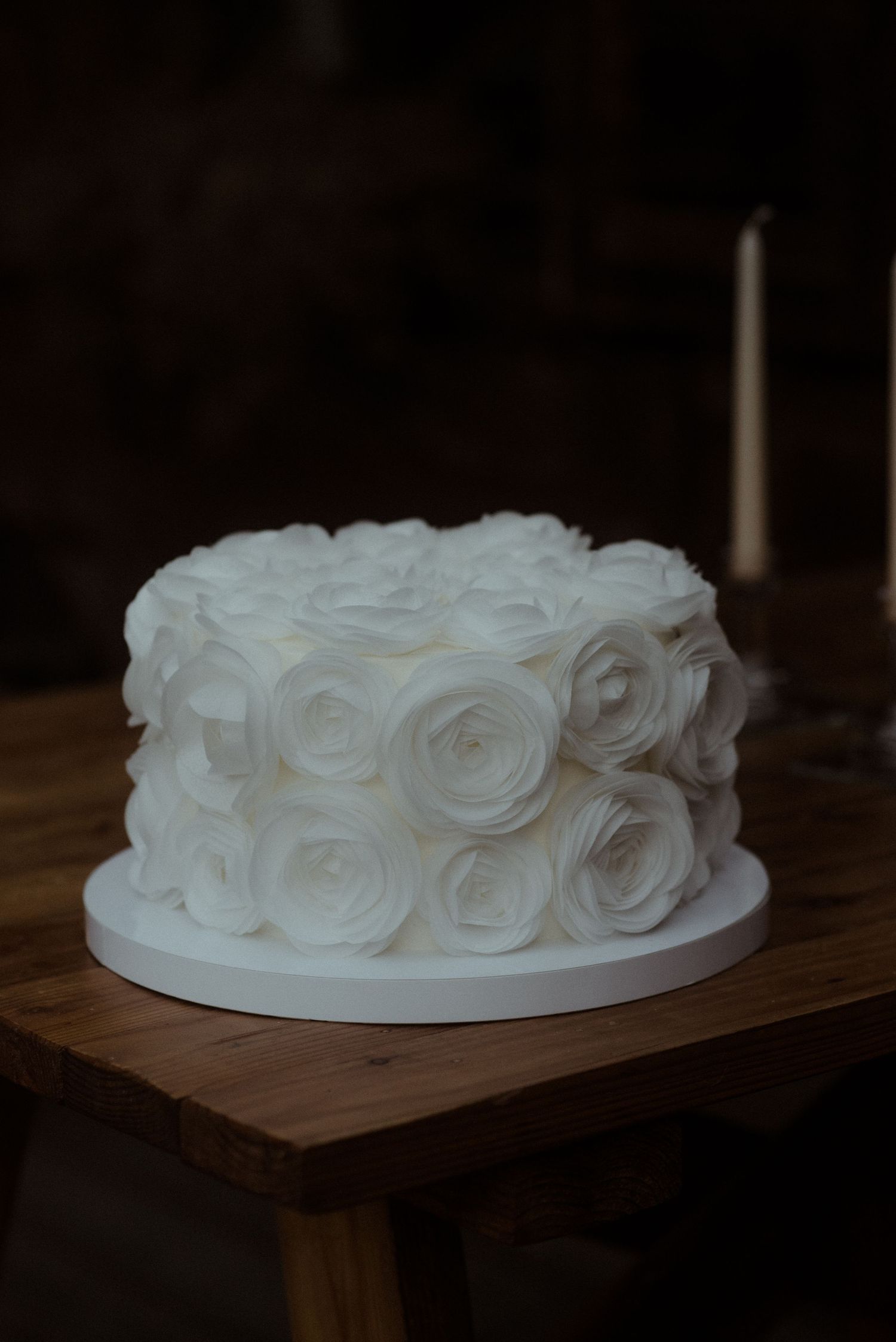 Elegant white wedding cake decorated with romantic rosette frosting details.
