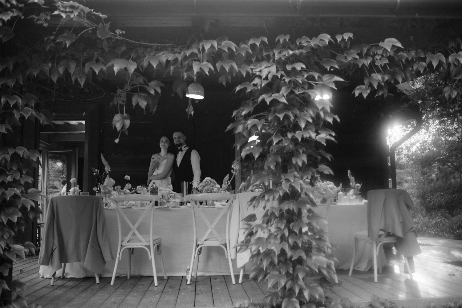An evening reception table setting under string lights with lush foliage in the background.