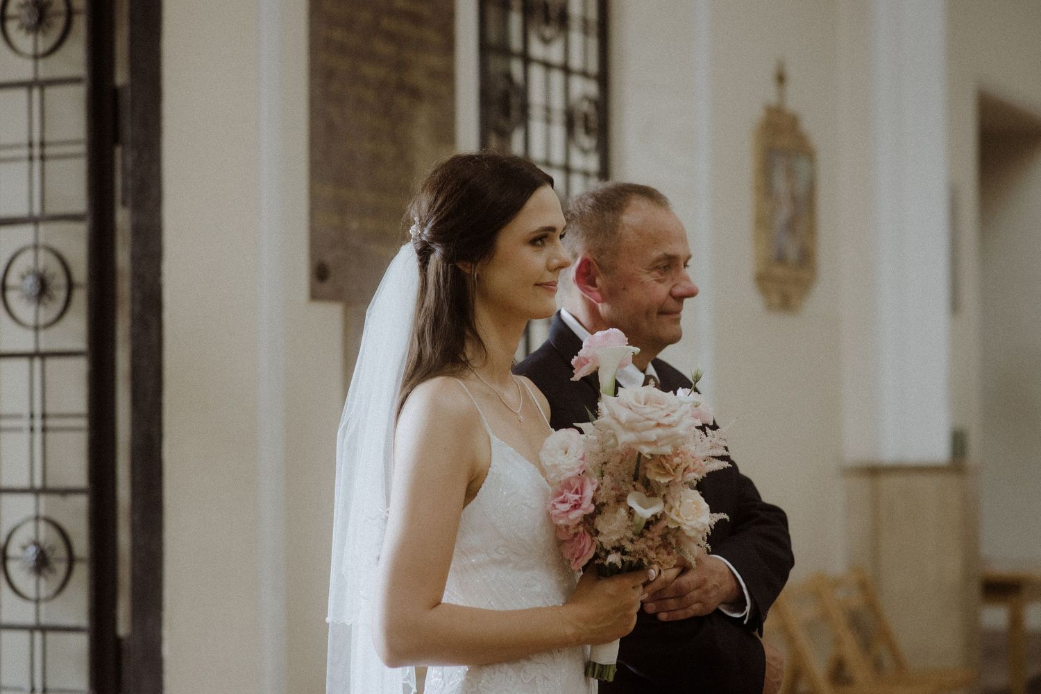 A couple embraces during an elegant church wedding ceremony with light streaming through windows.