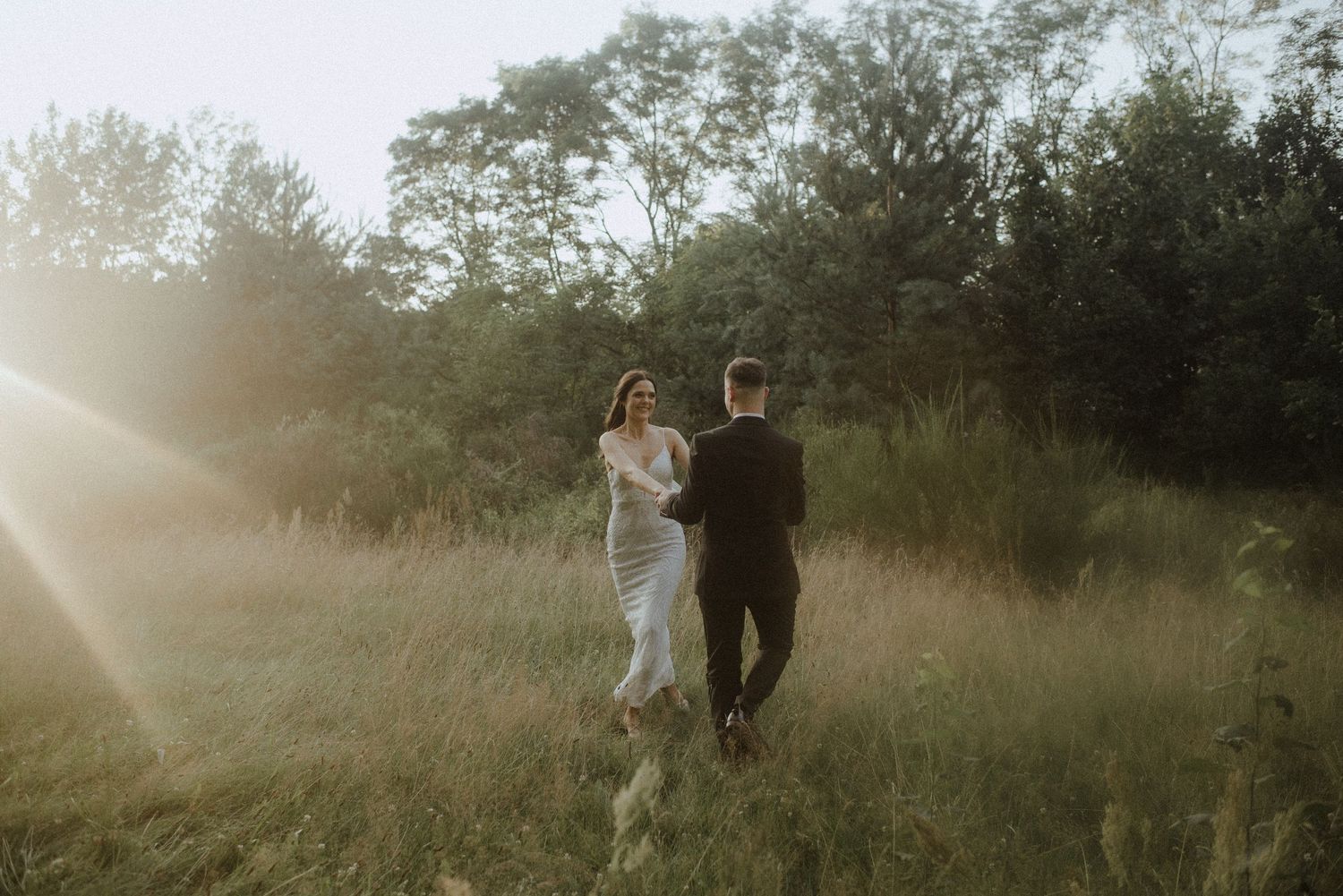 A romantic couple embracing in a sunlit meadow during golden hour.