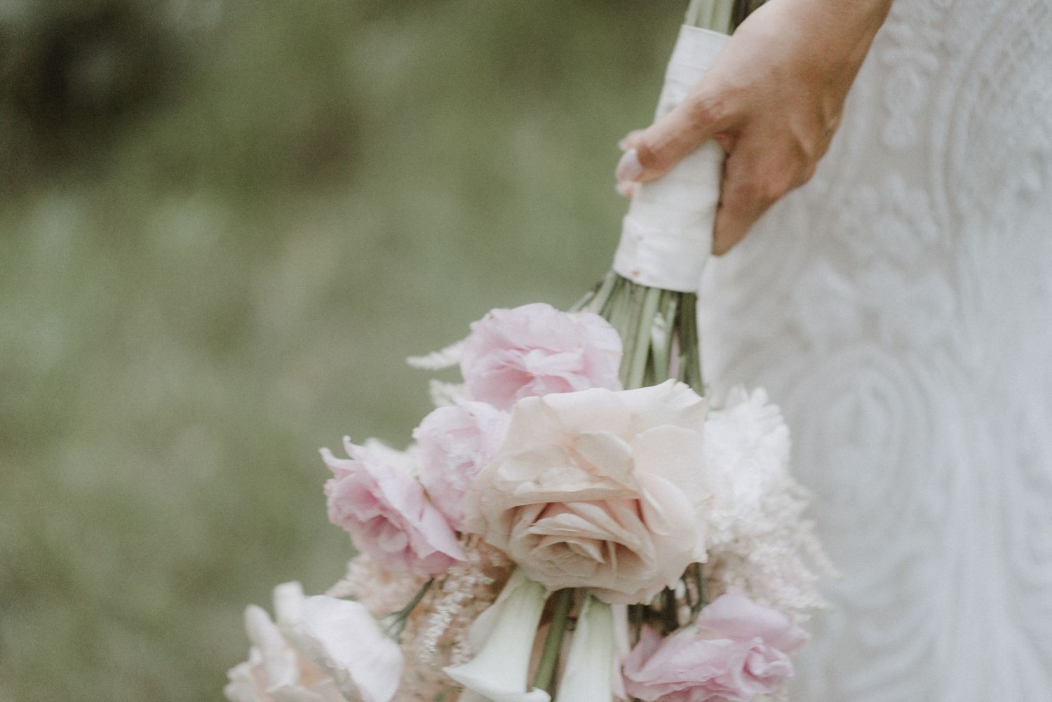 Close-up of a delicate pink and white wedding bouquet with soft focus roses and peonies.
