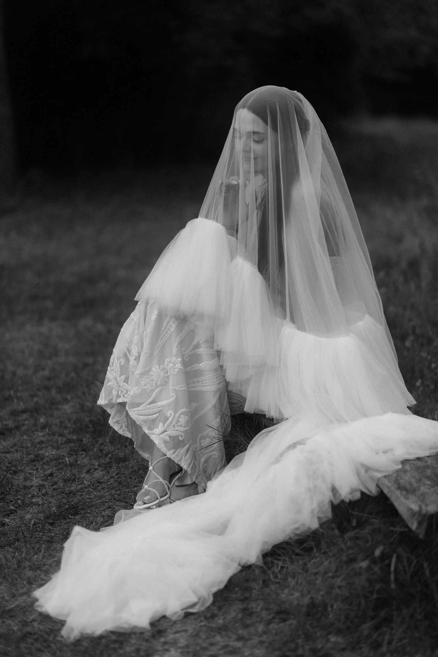 Ethereal black and white photo of a flowing bridal veil spread across grass.
