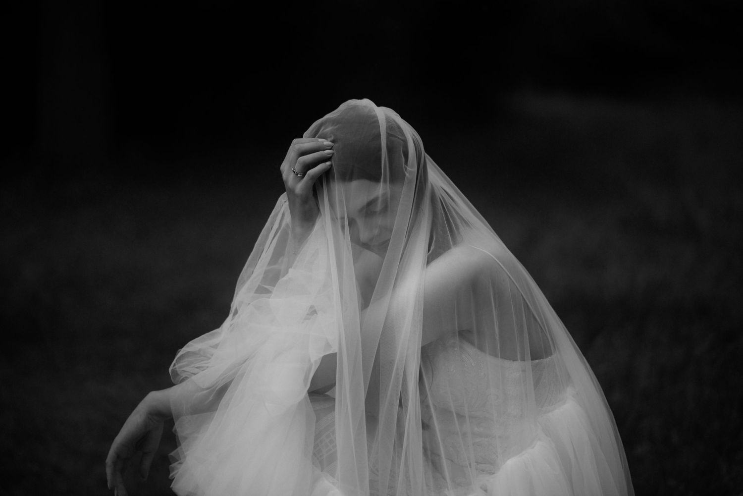 Elegant white wedding veil billowing in the breeze against a dark background.