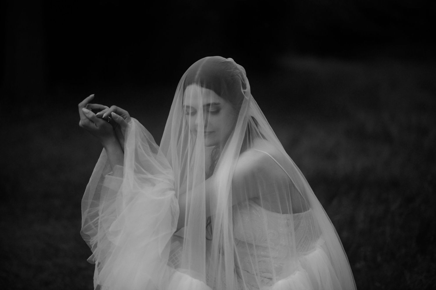 Artistic black and white portrait through a flowing white wedding veil.