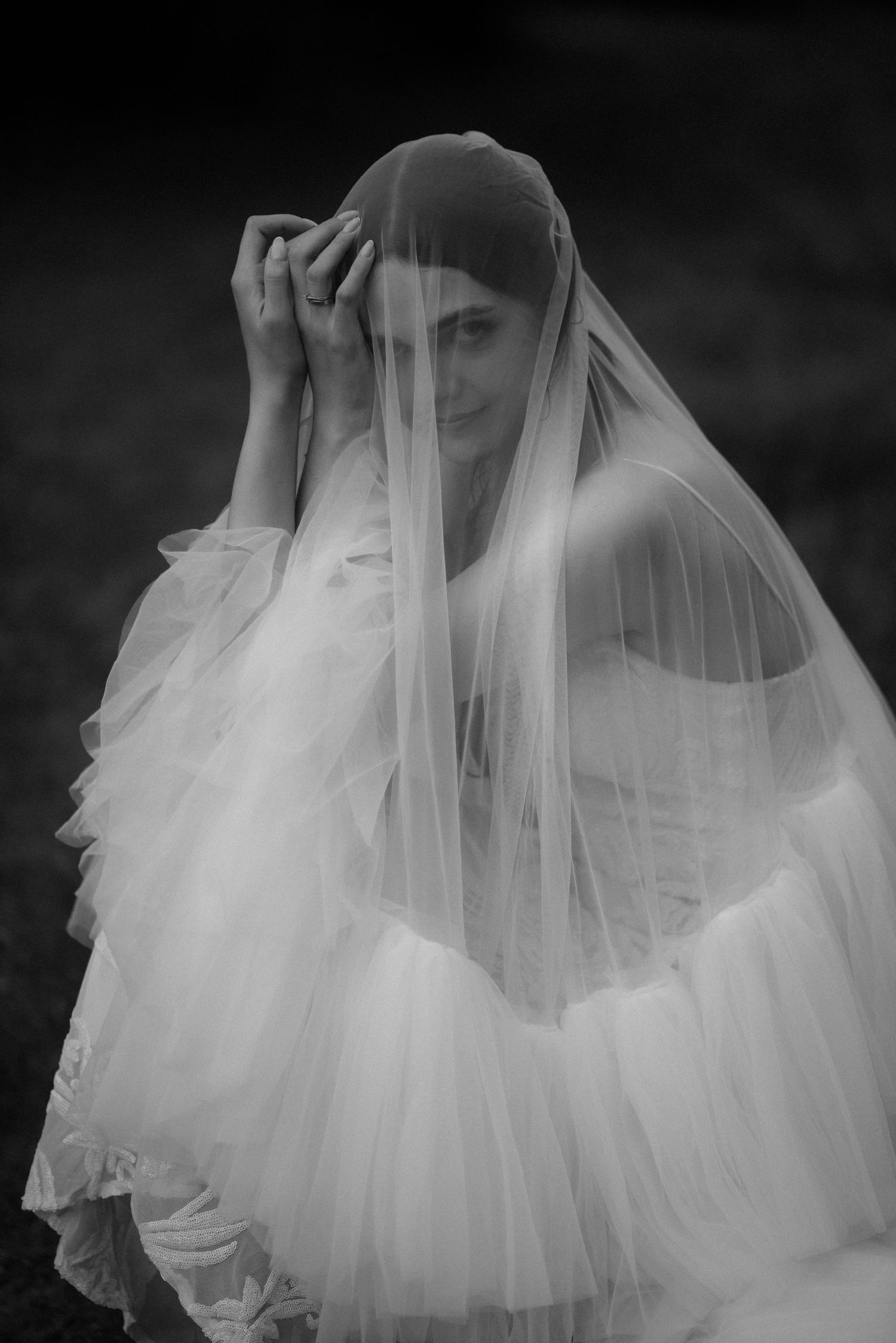 Ethereal black and white image of flowing white wedding dress tulle and veil details.