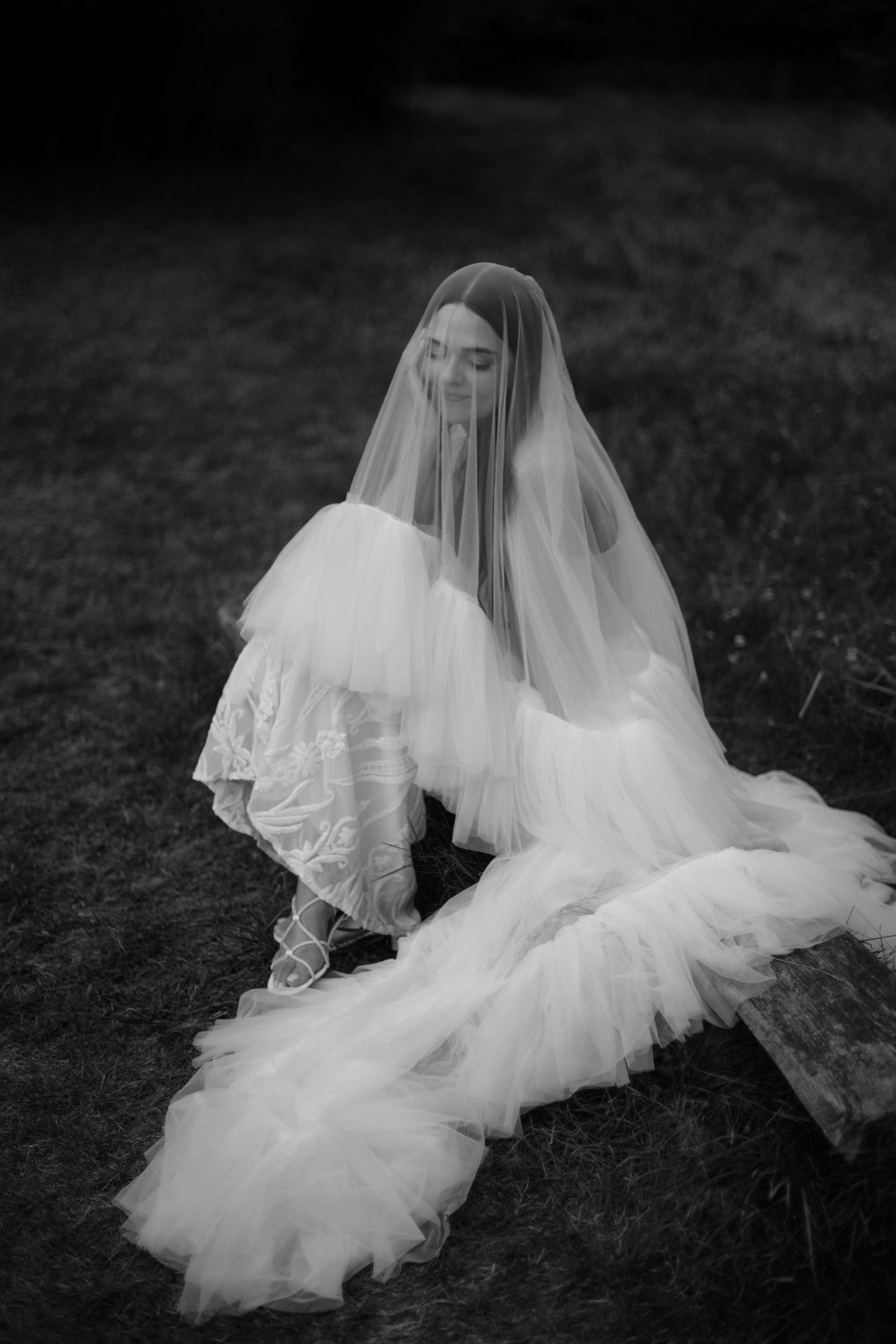 Artistic black and white photo of a bride's veil flowing across the ground.