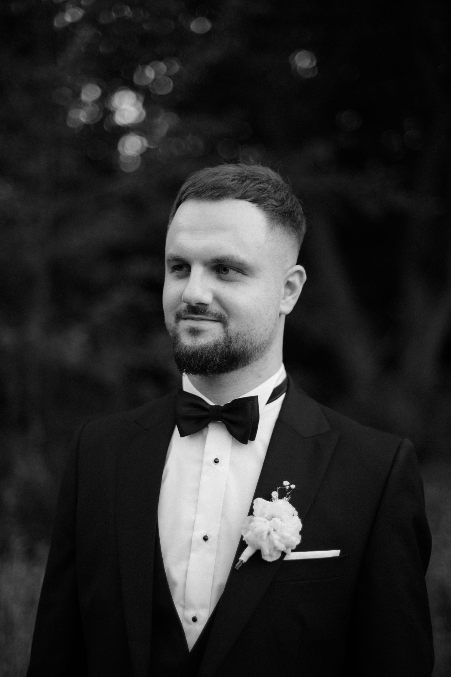 Classic black and white portrait of a groom in tuxedo with bowtie and boutonniere.
