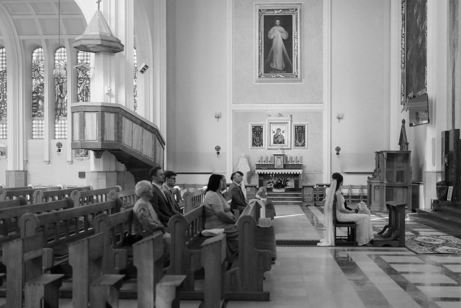 Interior view of a church with tall arched windows and architectural columns illuminated by natural light.