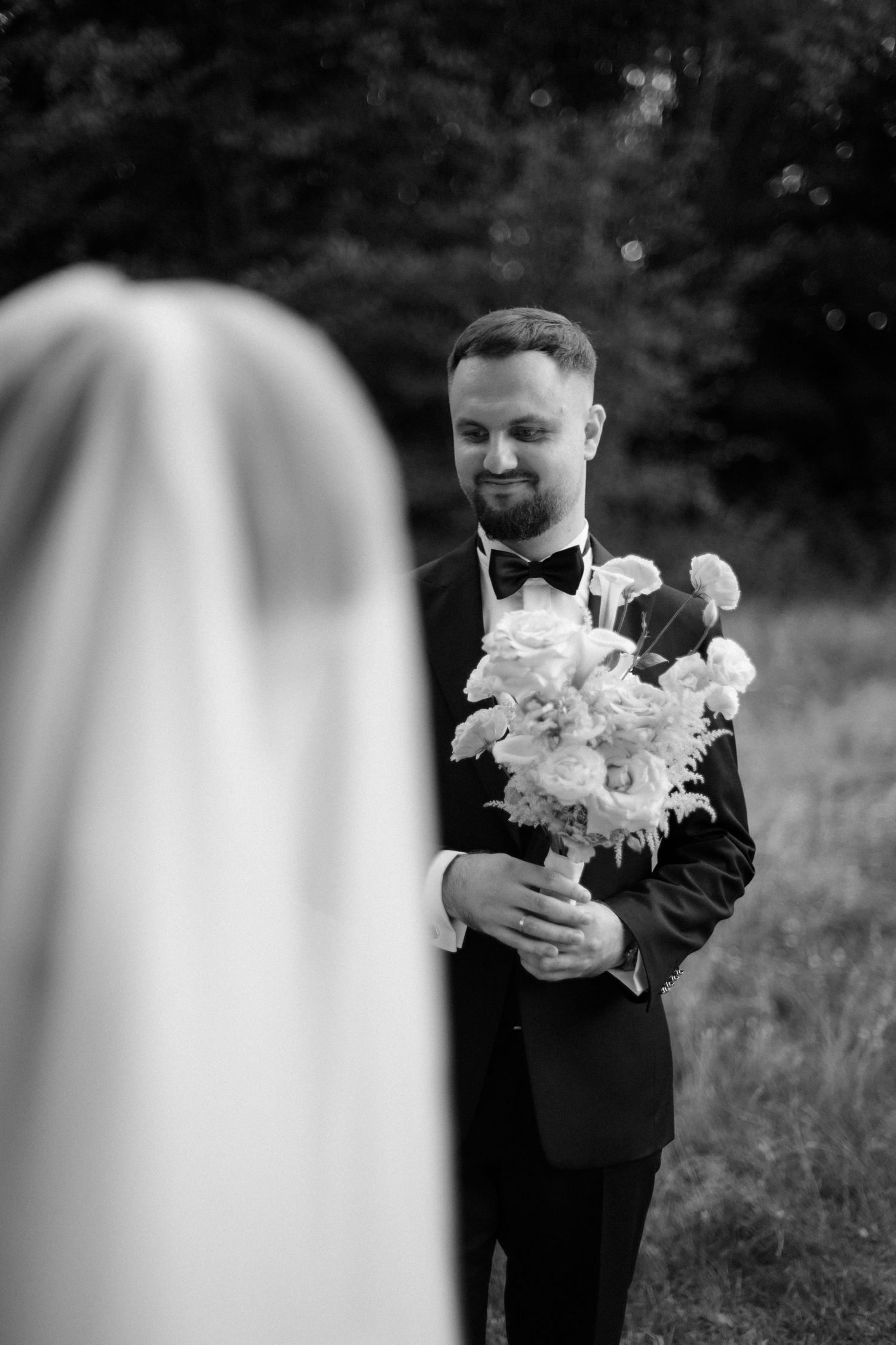 Black and white photo of hands holding white floral bouquet.