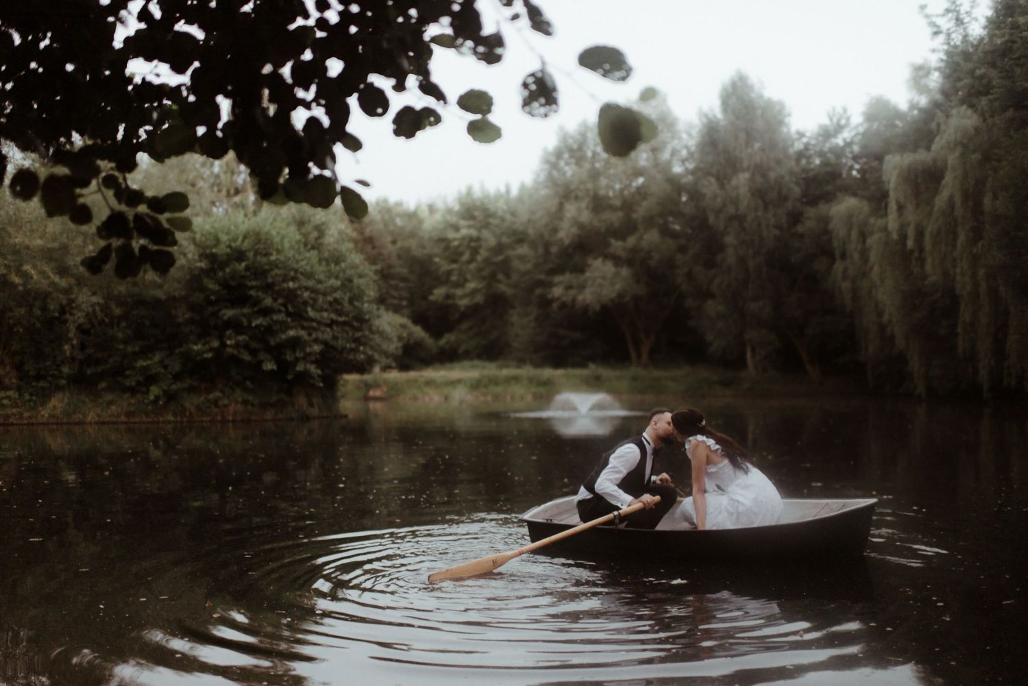 A sequence of candid photography showing people rowing in a boat across a peaceful lake surrounded by trees.