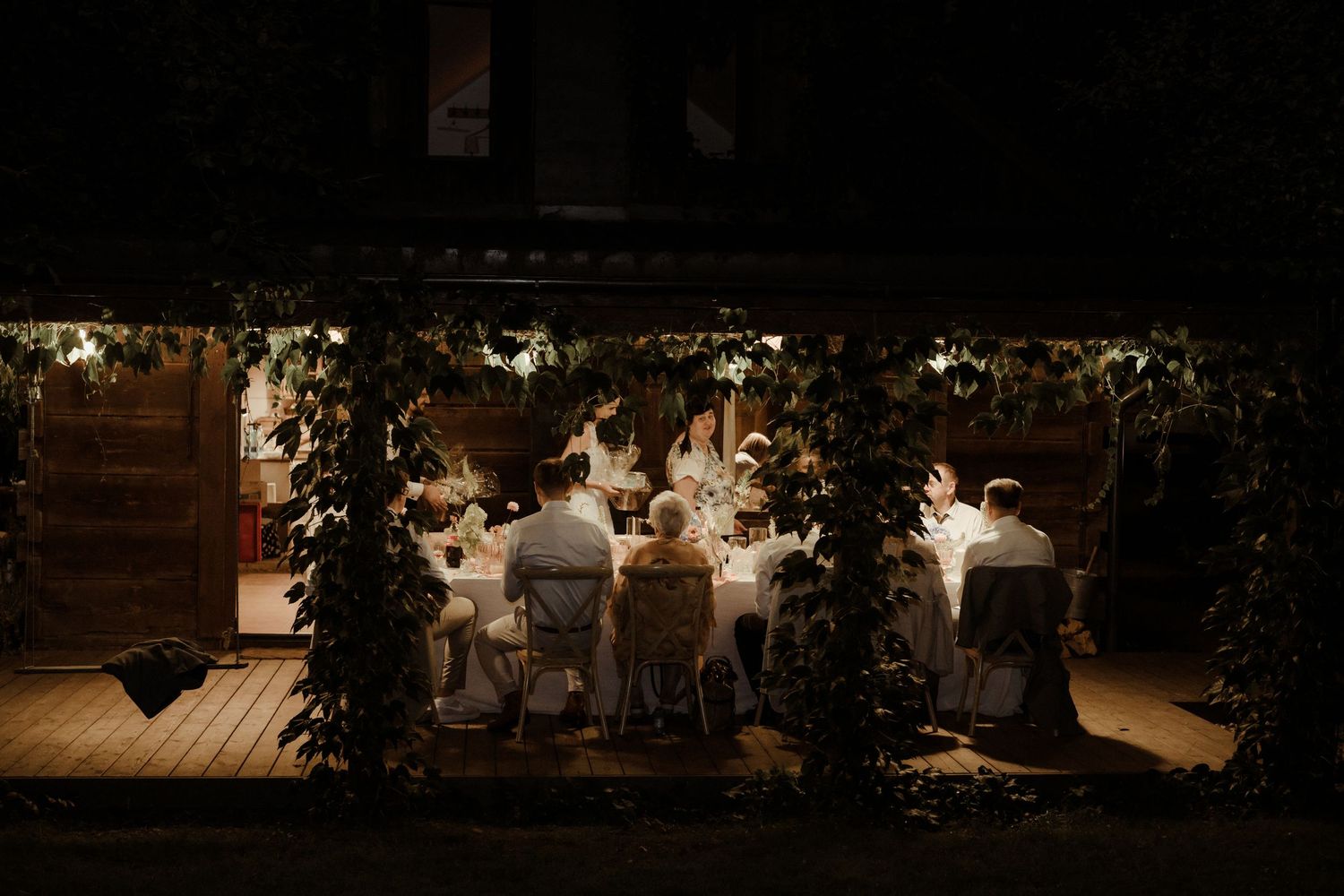 Rustic wooden ceremony setup with string lights hanging overhead at dusk creating a warm, intimate atmosphere.