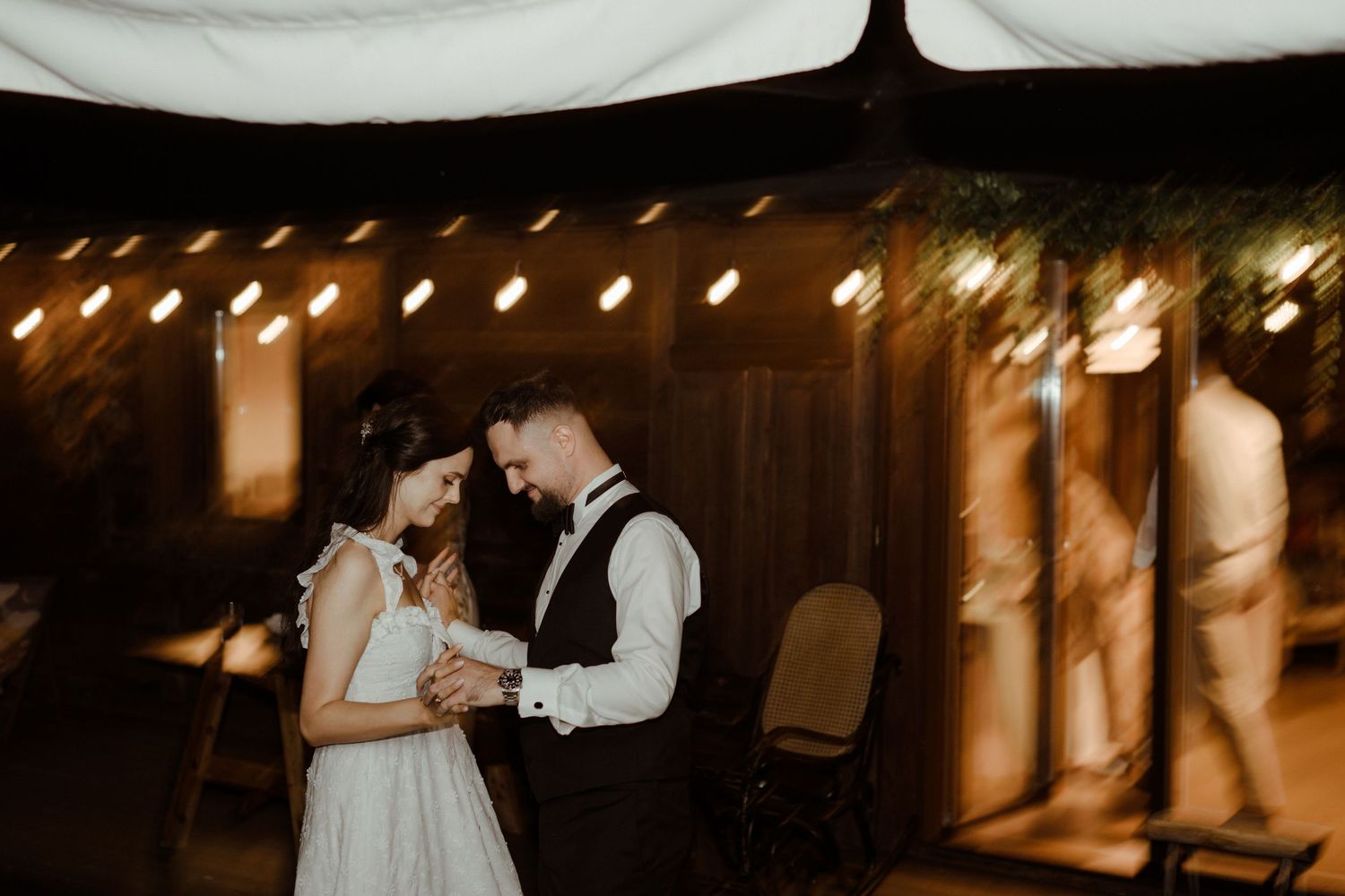 Romantic evening wedding venue with warm glowing lights and decorations creating an intimate atmosphere.