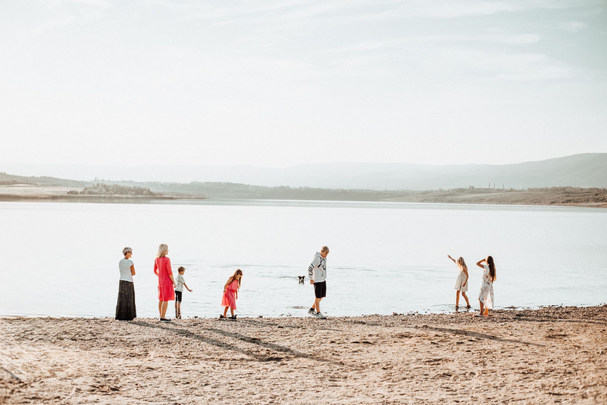 People enjoying a sunny day at the shoreline of a serene lake.