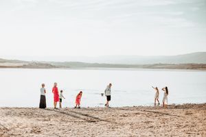 People enjoying a sunny day at the shoreline of a serene lake.