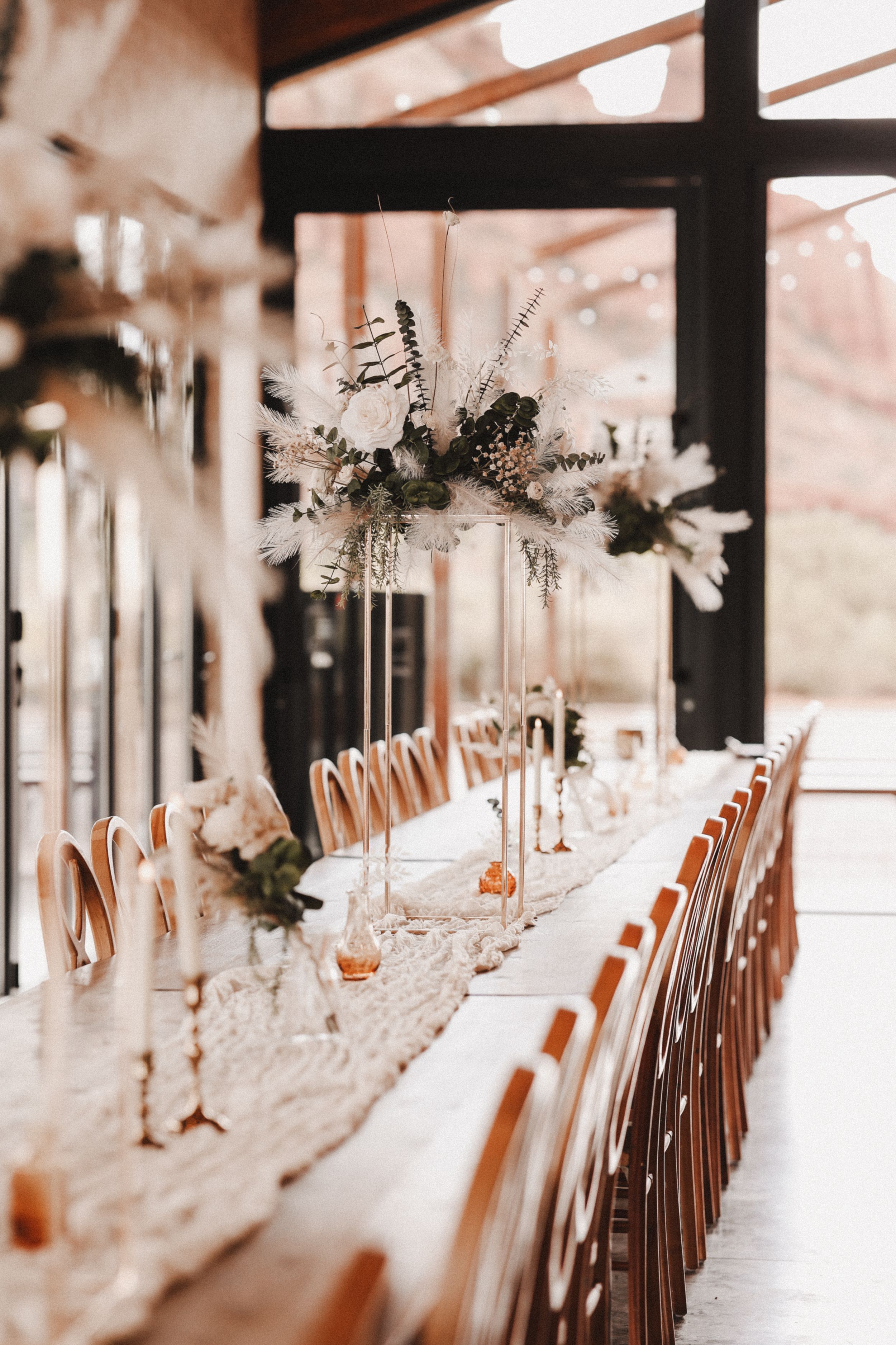 Elegant wedding reception table setup with long rows of place settings and floral centerpieces.